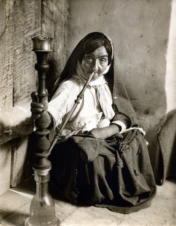 زنی درحال کشیدن قلیان در چای‌خانه‌ای در دامغان، سمنان، ۱۳۱۱ خورشیدی